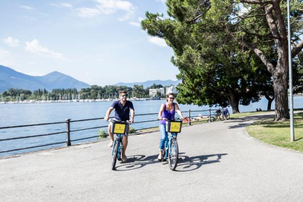 Un uomo  e una donna con le bici del bike sharing sul Lago Maggiore.