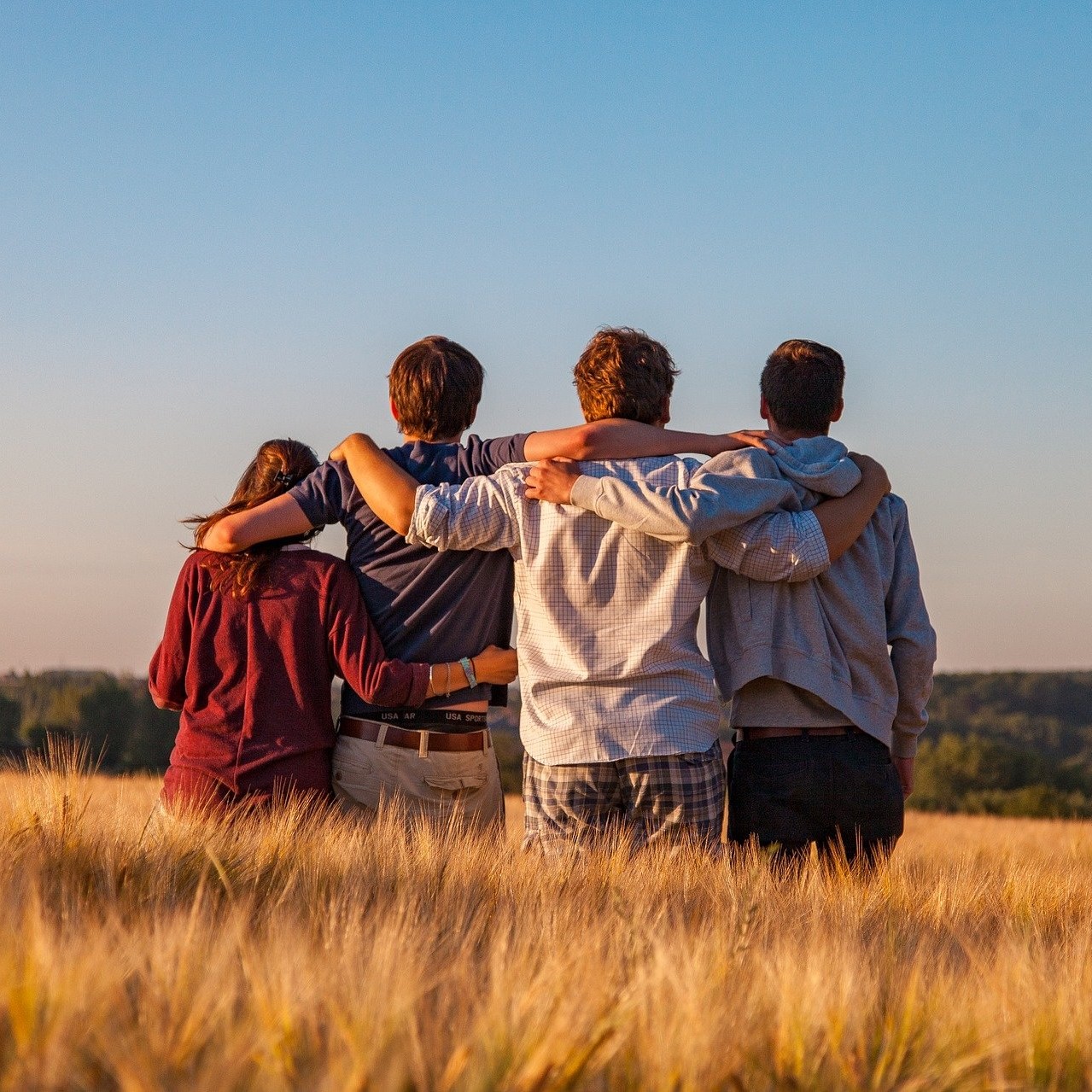 Gruppo di ragazzi abbracciati in un campo di grano