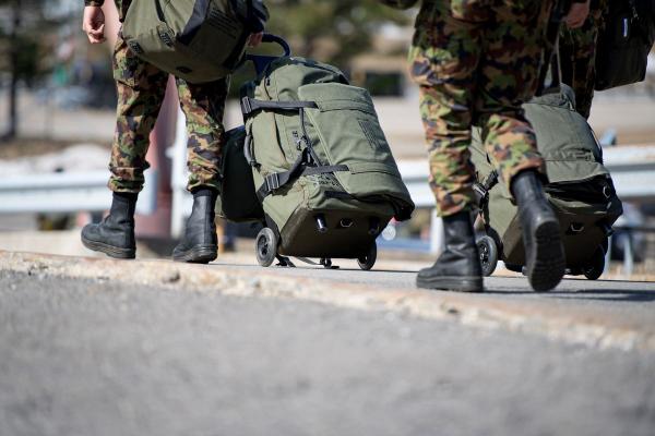 Due soldati camminano con le loro valigie.